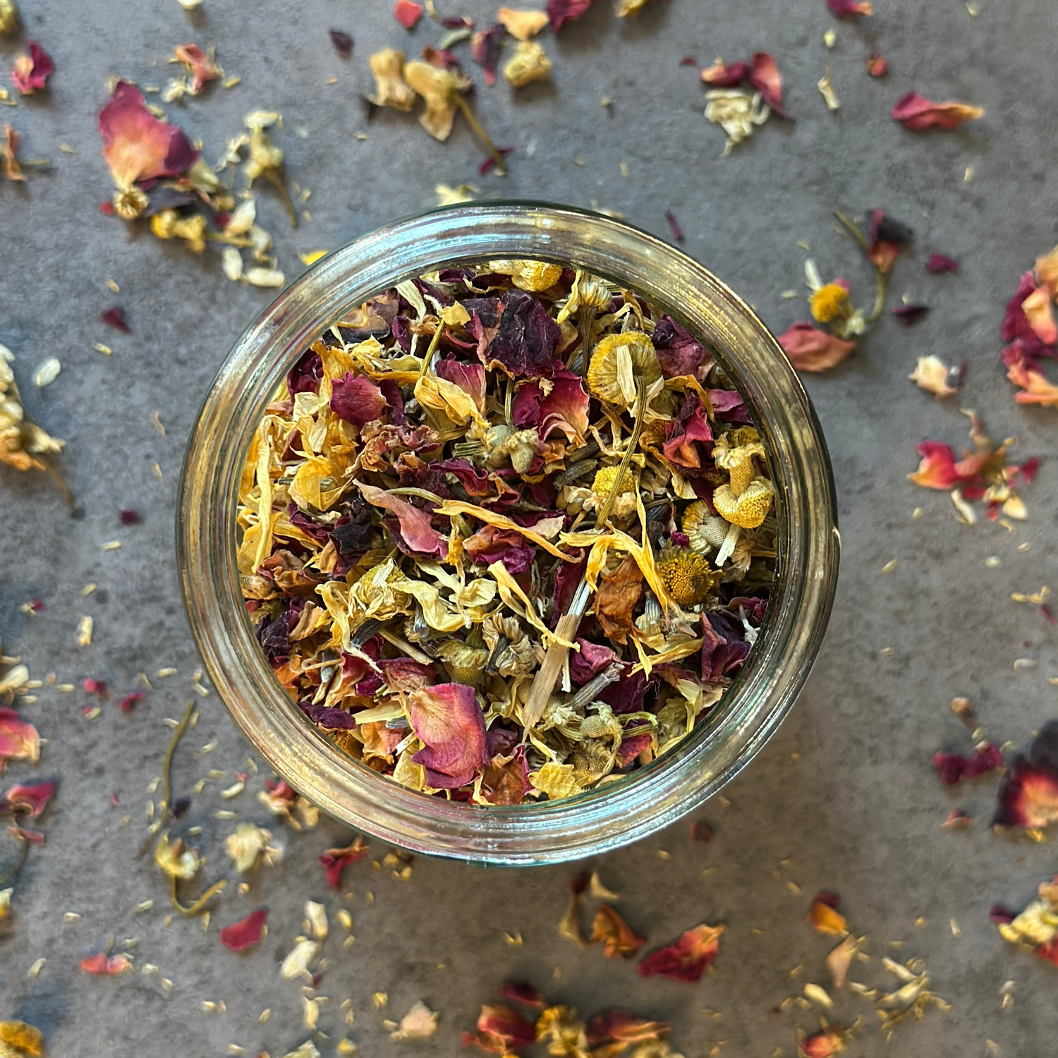 A jar holding a variety of herbs such as calendula, rose, and mugwort